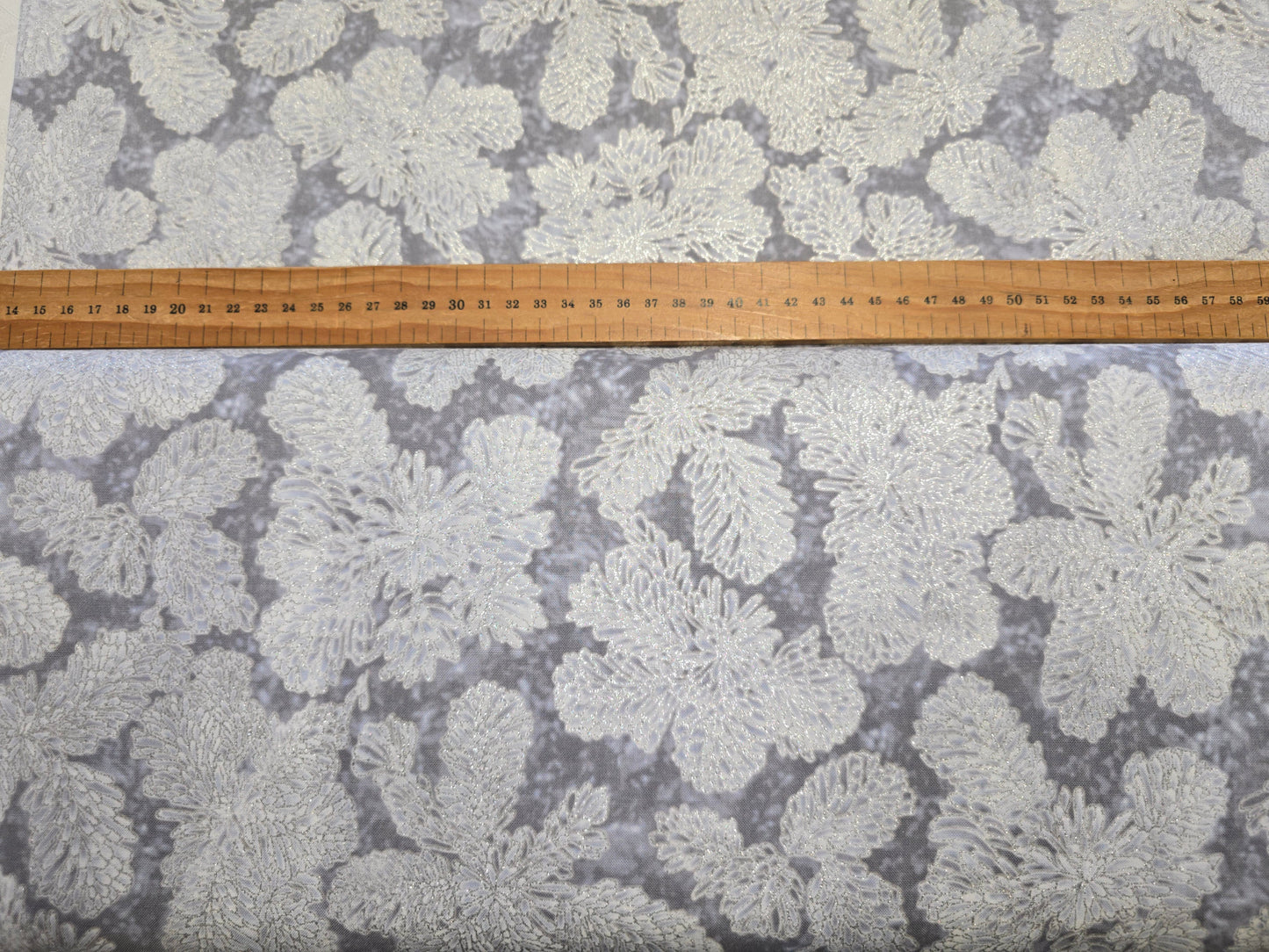 Fabric with a leaf pattern and a ruler at the top for scale.